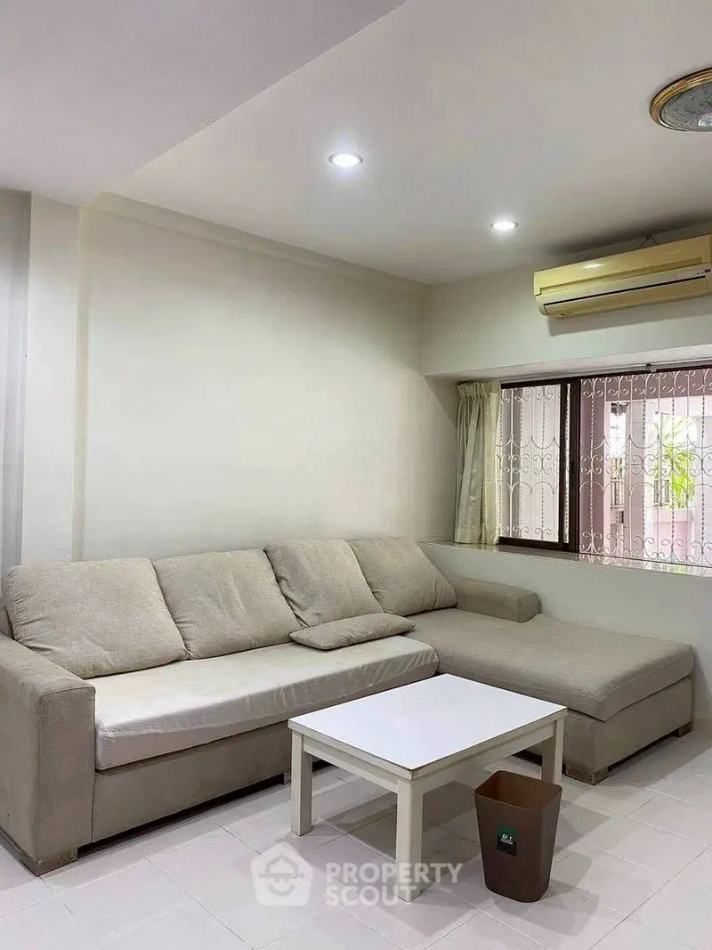 Spacious living room with cozy beige sofa and air conditioning, perfect for relaxation.