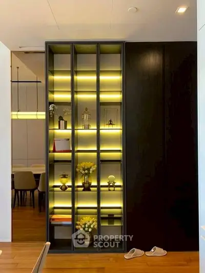 Elegant modern interior with illuminated shelving and dining area, showcasing contemporary design and warm lighting.