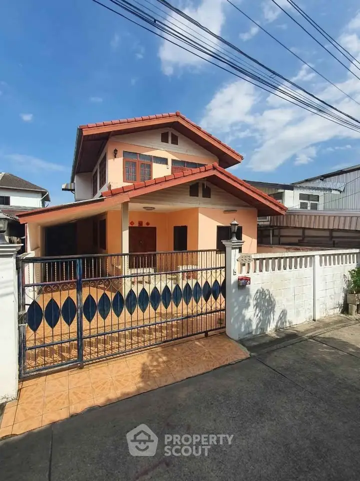 Charming two-story house with gated entrance and tiled patio in a suburban neighborhood.
