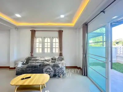 Spacious living room with modern sofa and large windows offering garden view