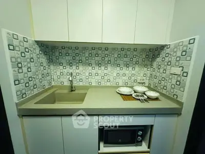 Compact kitchen with modern backsplash and built-in microwave, ideal for efficient cooking space.