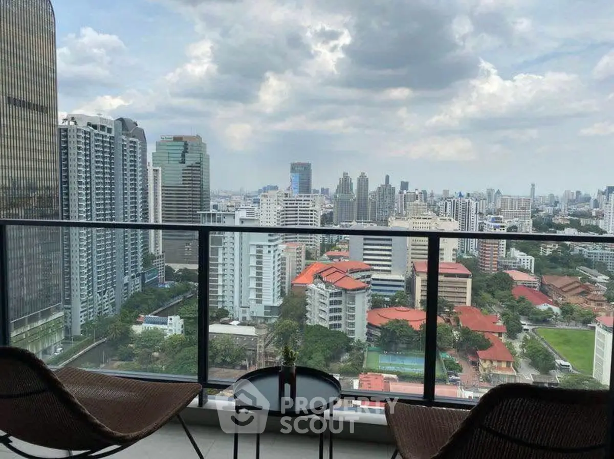 Stunning cityscape view from a high-rise balcony with modern seating, perfect for urban living.