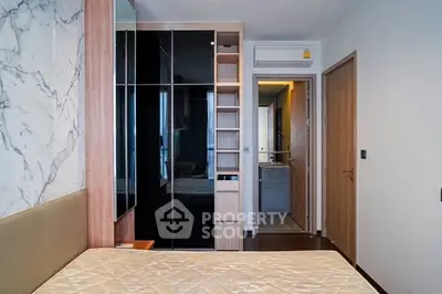 Modern bedroom with built-in wardrobe and marble accent wall in stylish apartment.