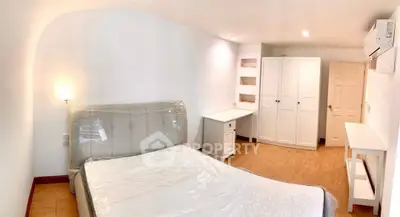 Spacious bedroom with modern furnishings and ample storage in a bright, airy apartment.