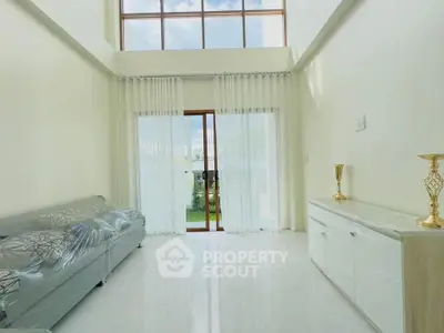 Spacious living room with high ceilings and large windows offering abundant natural light.