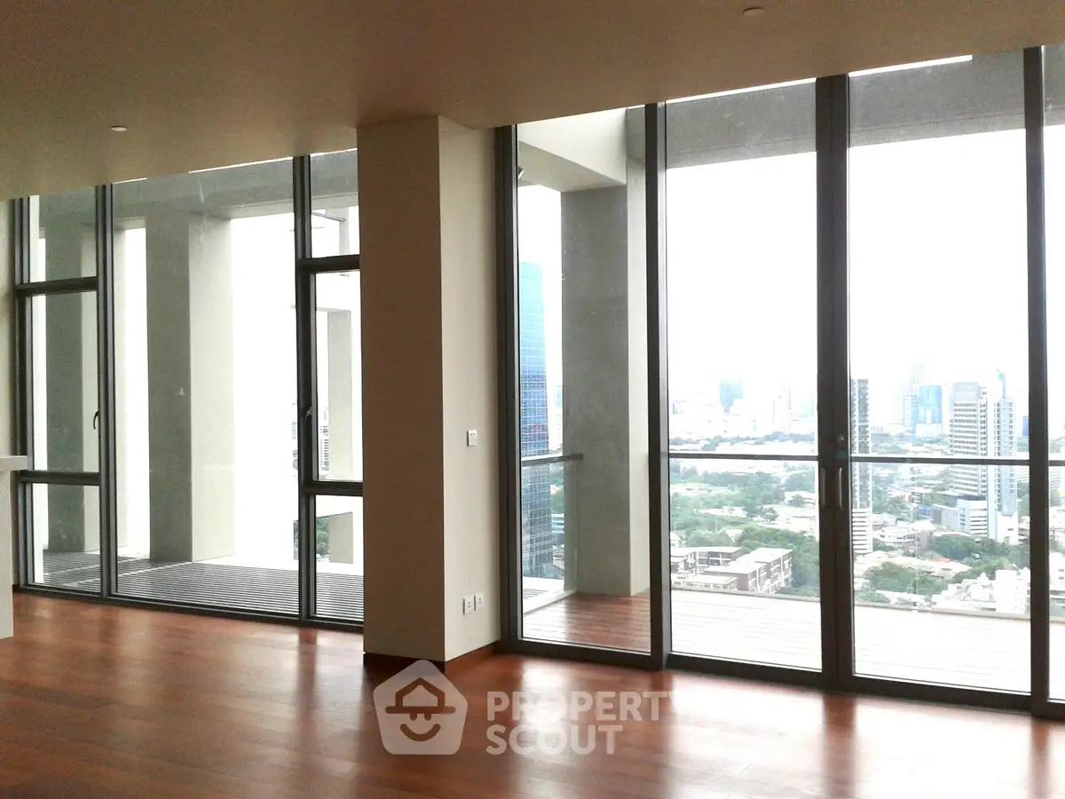 Spacious modern living room with floor-to-ceiling windows and stunning city view.