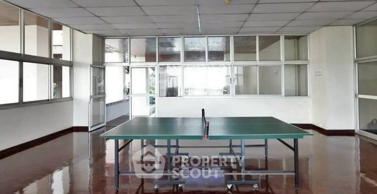 Spacious indoor recreational area with table tennis setup in modern building.