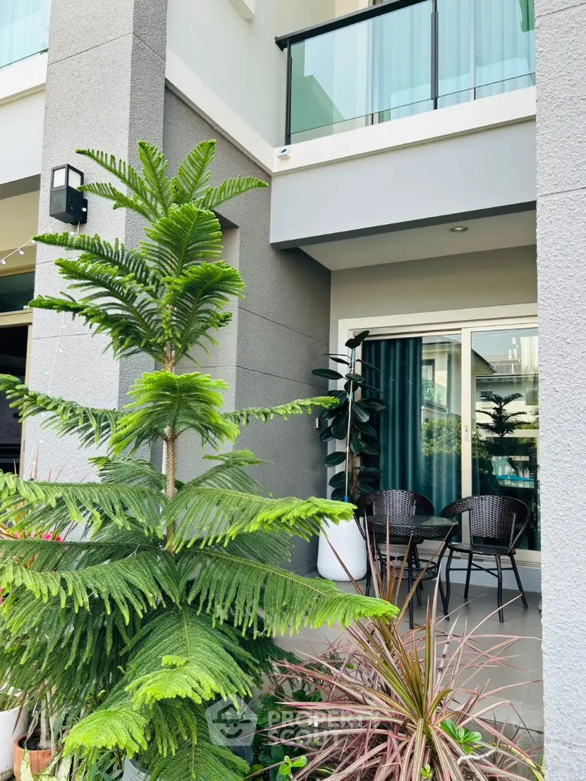 Modern building exterior with balcony and lush garden view