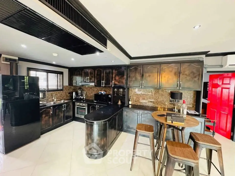 Luxurious modern kitchen with sleek black cabinetry and stylish island seating.