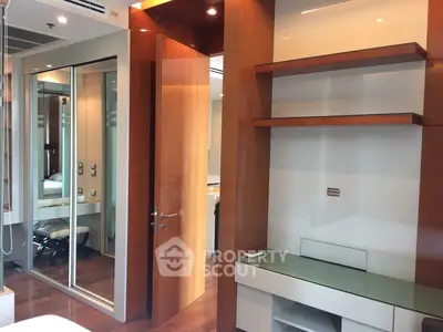 Modern bedroom with wooden accents and mirrored closet doors in a stylish apartment.
