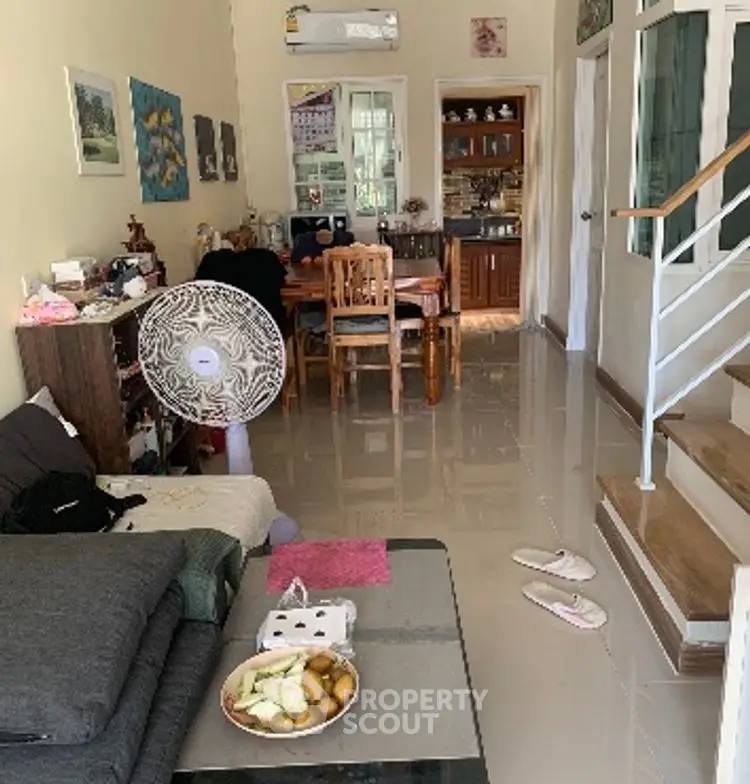 Cozy living room with dining area and staircase, featuring modern decor and natural light.