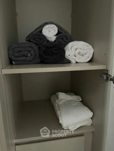 Organized linen closet with neatly folded towels and bathrobe