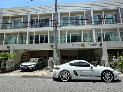 Modern townhouse with sleek design and luxury cars parked in front, showcasing urban living.