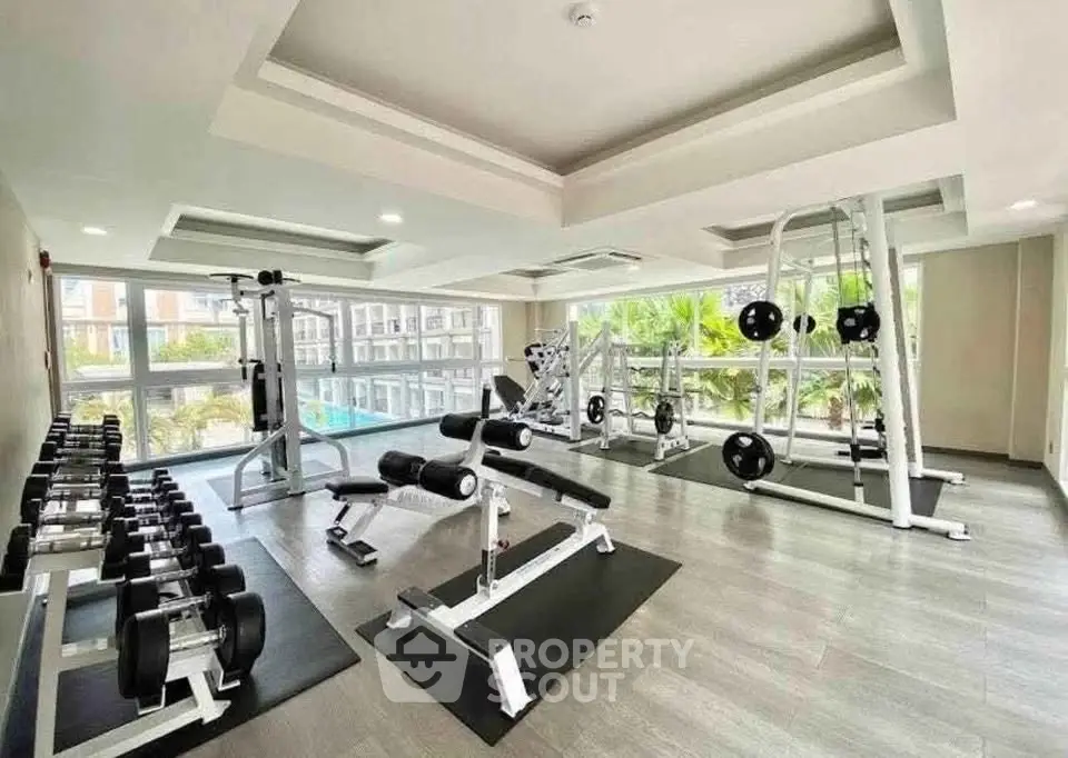 Modern gym with state-of-the-art equipment and large windows overlooking a pool area.