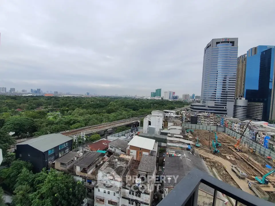 Stunning cityscape view from high-rise balcony overlooking urban development and lush greenery.