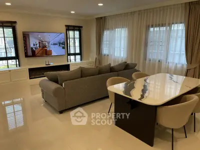 Spacious living room with modern decor, large TV, and elegant dining area, perfect for entertaining.