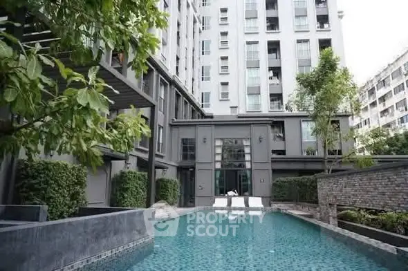 Luxurious modern apartment complex with serene swimming pool and lush greenery.