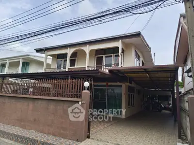 Spacious two-story house with gated driveway and covered parking in a suburban neighborhood.