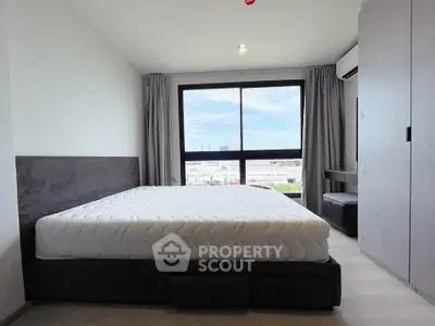 Spacious bedroom with large window offering a stunning city view, modern furnishings, and ample natural light.