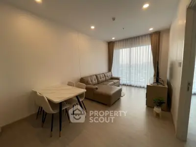 Modern living room with cozy sofa and dining area, featuring large window with city view.