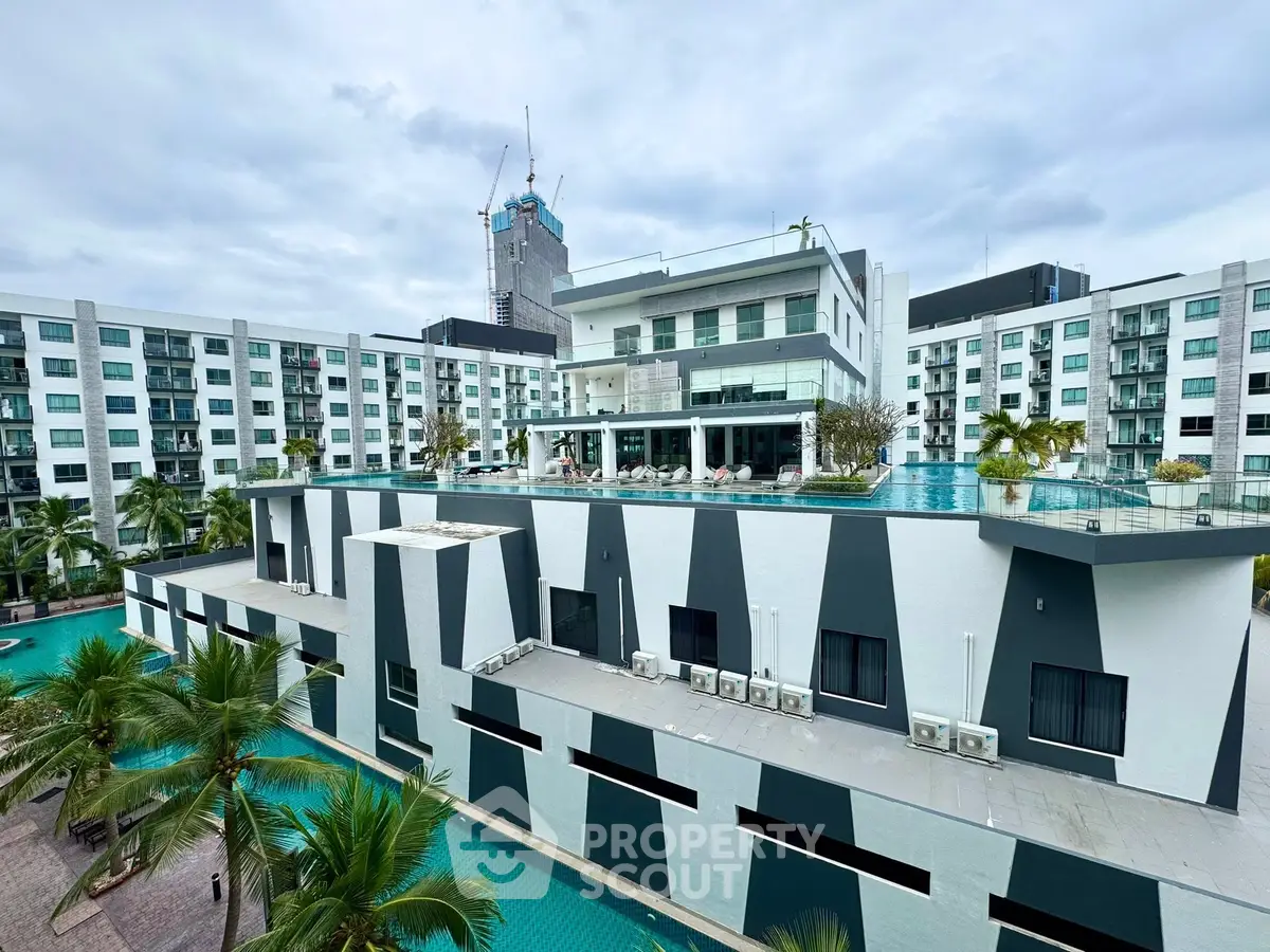 Modern apartment complex with rooftop pool and palm trees, showcasing luxury living.