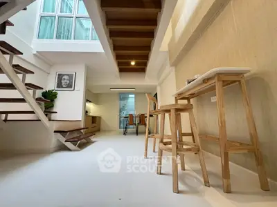 Modern open-plan living space with wooden staircase and minimalist decor