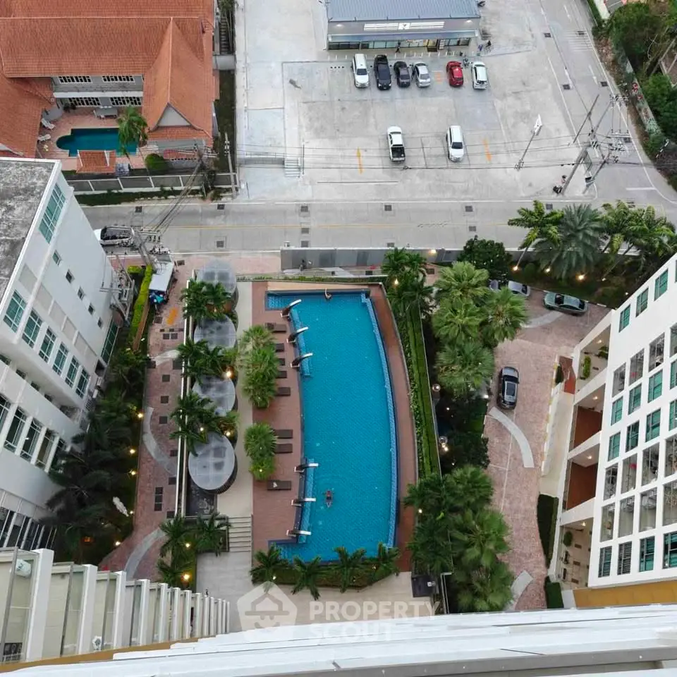 Stunning aerial view of luxury condominium with pool and lush landscaping, perfect for urban living.