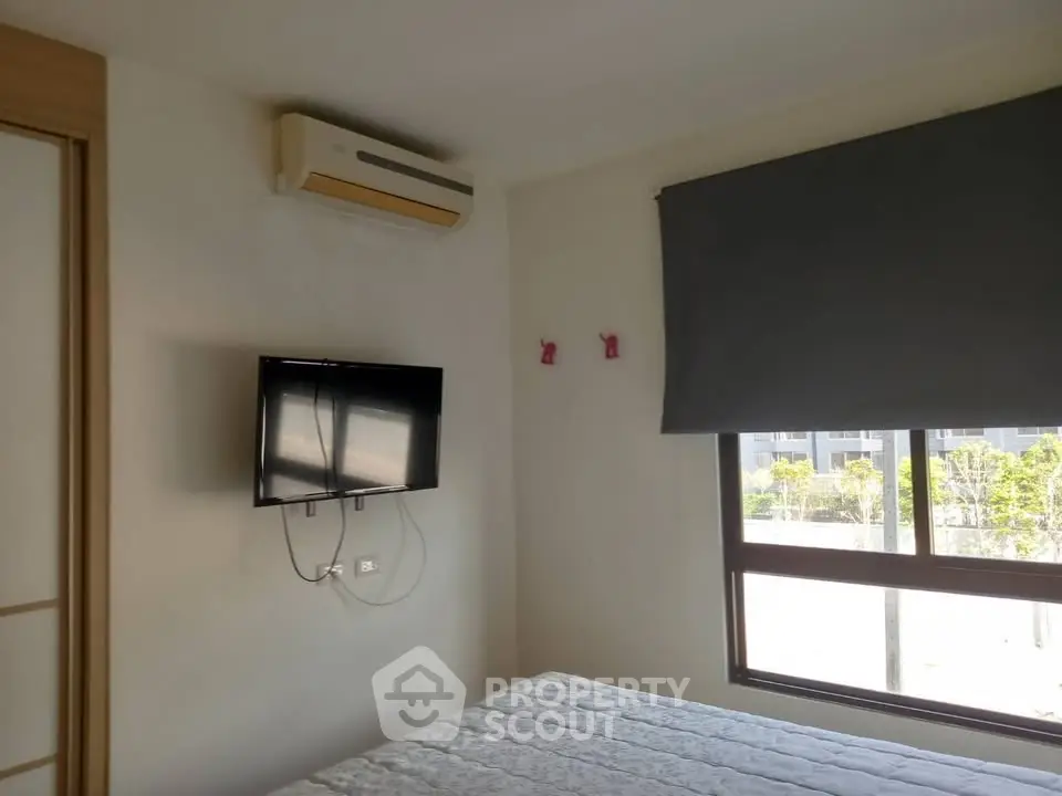 Modern bedroom with wall-mounted TV and air conditioning unit.