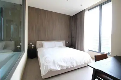 Modern bedroom with large windows and minimalist decor in a high-rise apartment.