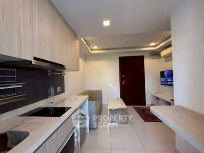 Modern compact living room with integrated kitchen, featuring sleek cabinetry and cozy seating area.