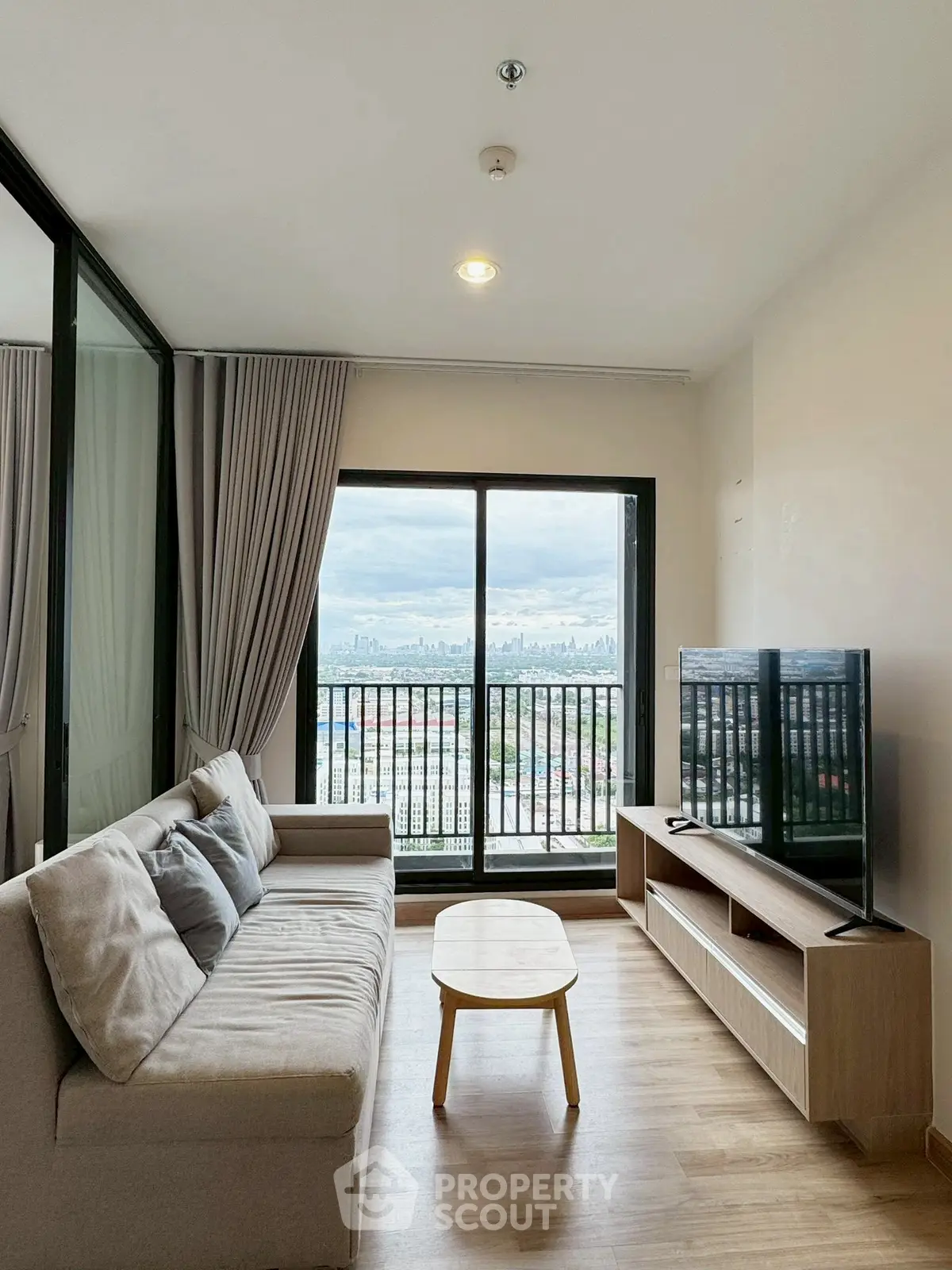 Modern living room with city view, featuring a cozy sofa and entertainment unit, perfect for relaxation.