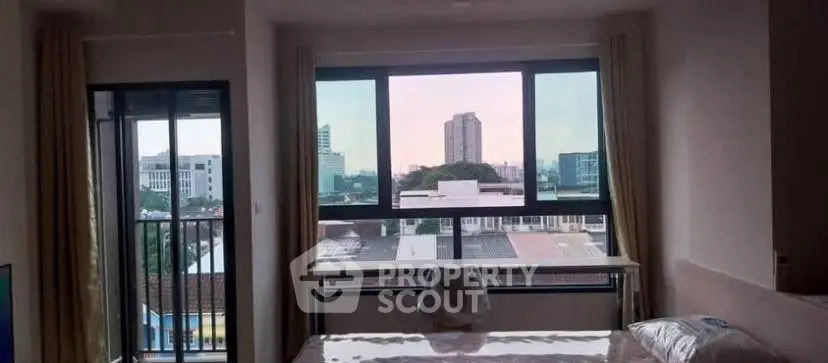 Spacious bedroom with large windows offering stunning city views and natural light.