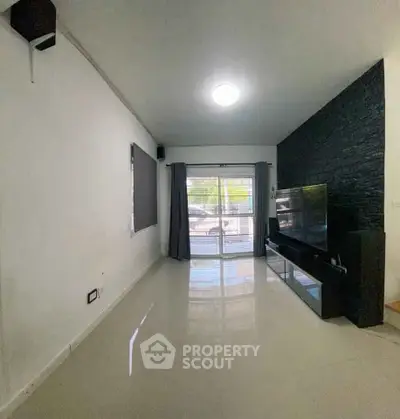 Spacious modern living room with sleek black accent wall and large window for natural light.
