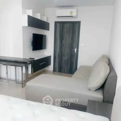 Modern living room with sleek furniture and wall-mounted TV in a stylish apartment.