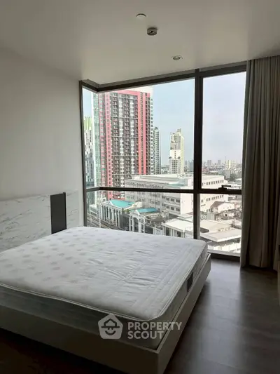 Modern bedroom with city view and large windows in high-rise apartment