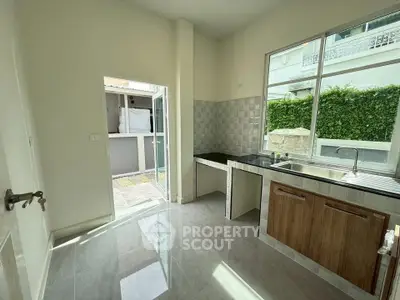 Modern kitchen with open layout and garden view, featuring sleek countertops and ample natural light.