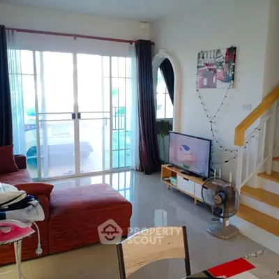 Spacious living room with modern decor and natural light, featuring a cozy sofa and entertainment setup.