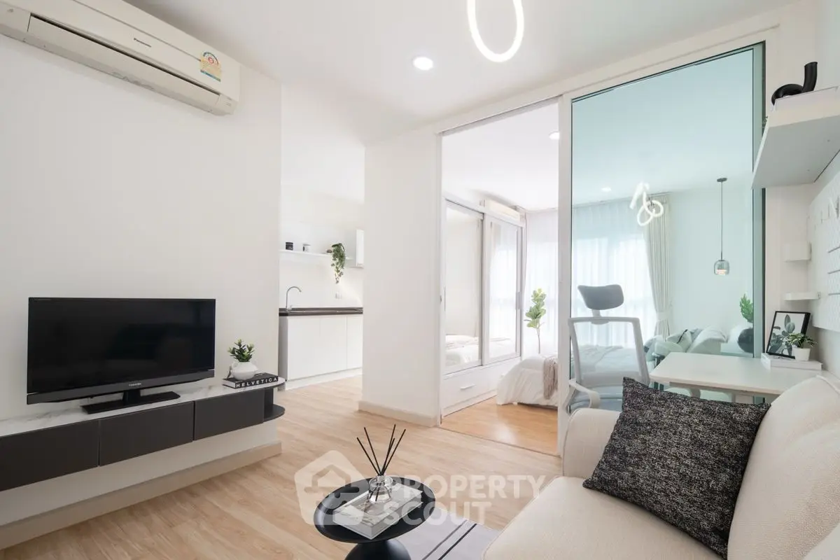 Modern open-plan living room with sleek kitchen and cozy bedroom, featuring minimalist decor and natural light.