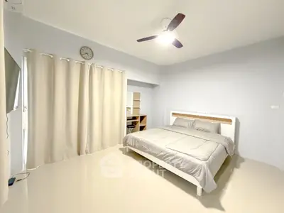 Spacious bedroom with modern decor and natural light, featuring a comfortable bed and study area.