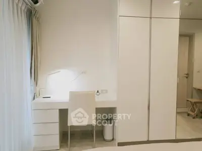 Modern bedroom with sleek white furniture and study area, perfect for urban living.