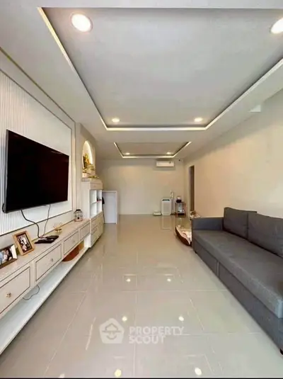 Spacious modern living room with sleek design and large TV, perfect for relaxation.
