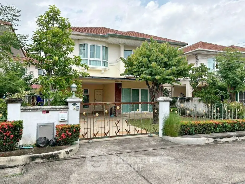 Charming two-story house with lush garden and gated entrance in a serene neighborhood.