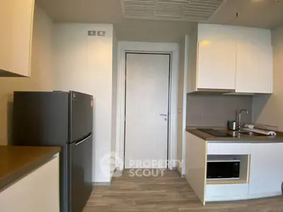 Modern kitchen with sleek cabinets, fridge, and built-in appliances in a compact layout.