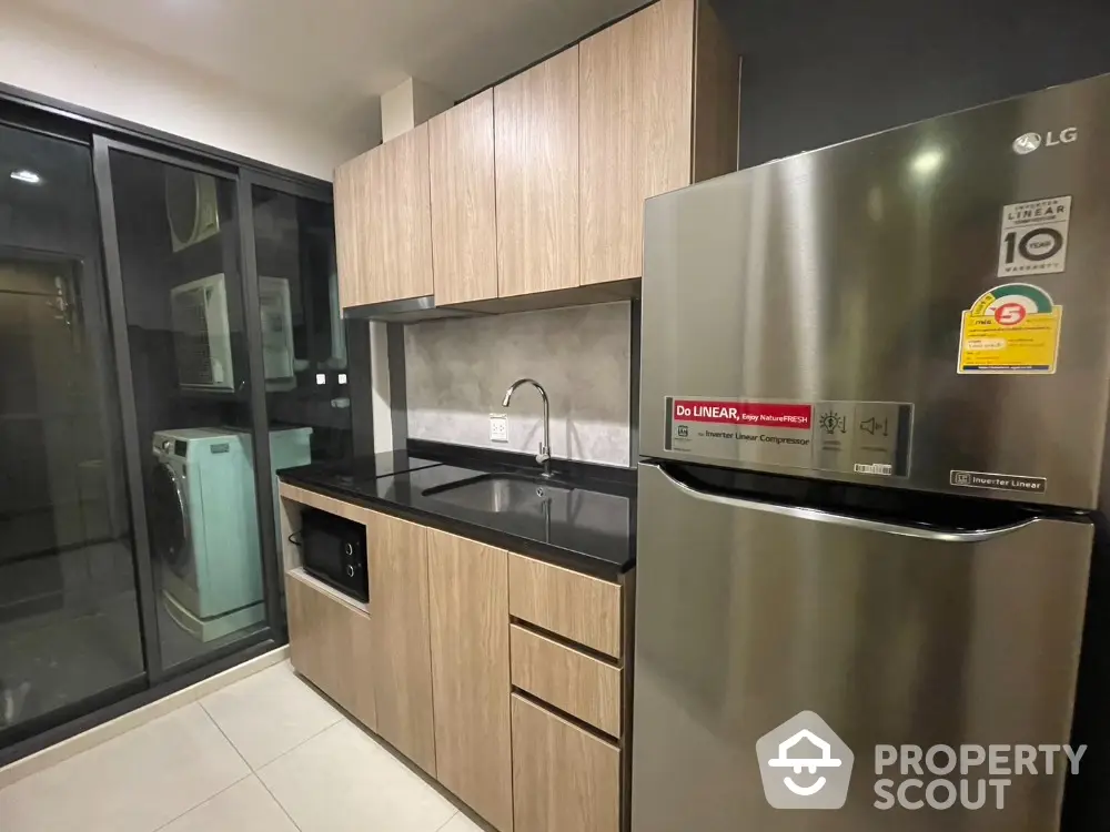 Modern kitchen with sleek appliances and wooden cabinetry in a stylish apartment.