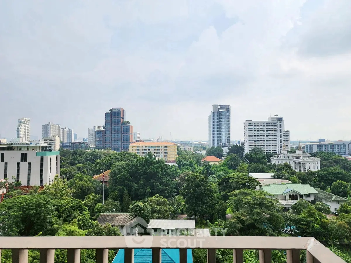 Stunning cityscape view from a high-rise balcony overlooking lush greenery and modern buildings.
