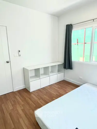Bright minimalist bedroom with wooden flooring and modern storage unit