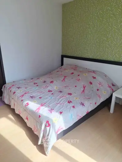 Cozy bedroom with floral bedding and green accent wall, perfect for relaxation.