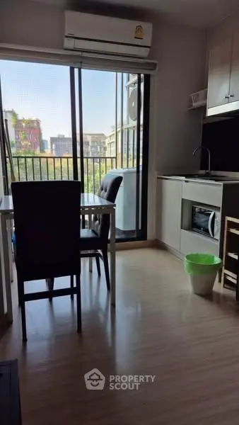 Modern apartment with open kitchen and balcony view, featuring sleek furniture and natural light.