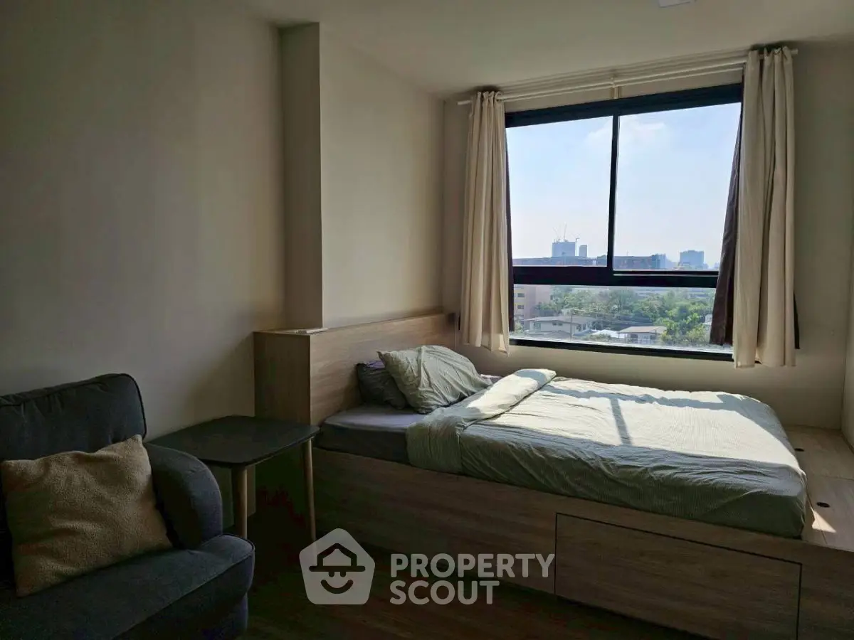 Cozy bedroom with large window and city view, featuring a comfortable bed and stylish decor.