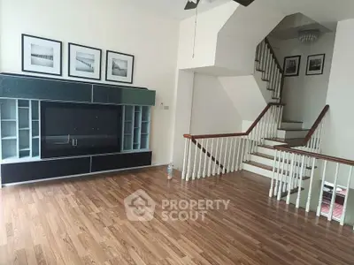 Spacious living room with modern entertainment unit and elegant staircase